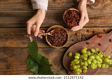 Woman with sweet raisins in bowls at table