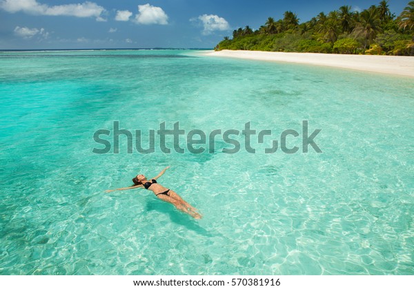 女は海で泳いでリラックスする 島での幸せな生活 熱帯の海岸の水晶のように青い海に白い砂 パラダイスでの休暇 オーシャンビーチリラックス モルディブ諸島へ旅行 の写真素材 今すぐ編集