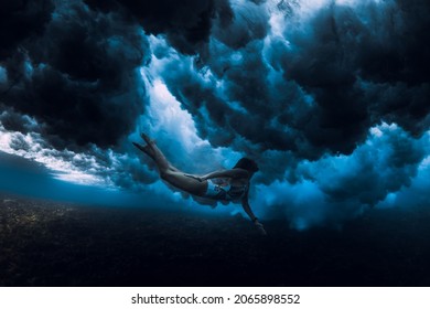 Woman swim underwater with ocean wave. Duck dive under wave