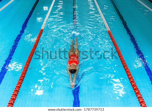 Woman swimmer swims backstroke in the pool. Top\
view, backstroke training