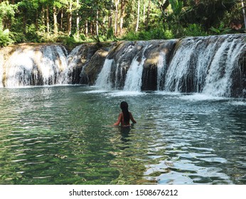 Woman Swimming Alone At The Tropical Wild Nature Of Waterfalls, Cambugahay Falls In Siquijor Island In Philippines