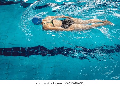 Woman swimming with swimming hat and swimsuit in swimming pool - Powered by Shutterstock