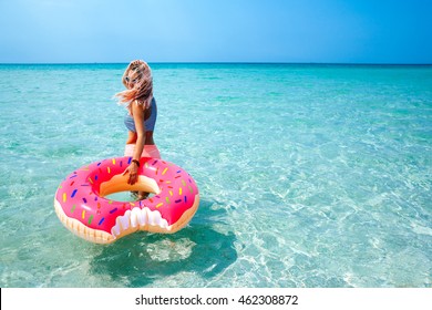 Woman swimming with inflatable donut on the beach in summer sunny day
