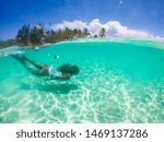 Woman swimming on a tropical beach with blue water and palm trees - Coron, Philippines