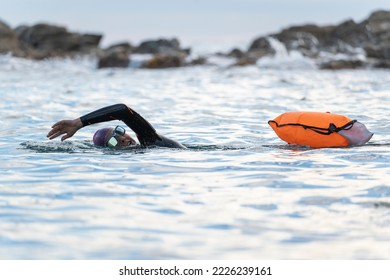 Woman swimming in open water with wetsuit and buoy