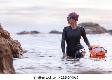 Woman swimming in open water with wetsuit and buoy