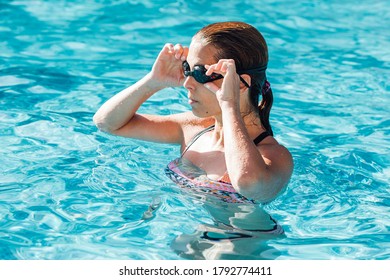 Woman In Swimming Pool Putting On Swimming Goggles