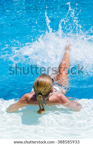 Woman at the swimming pool splashing water with her legs