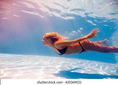 Woman swimming underwater in a blue pool