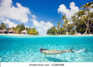 Woman swimming underwater in clear tropical waters in front of exotic island - Powered by Shutterstock