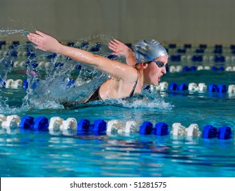 woman swims using the butterfly stroke in indoor pool