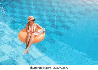 Woman in a swimsuit floating in inflatable circle in swimming pool and surfing the internet websites at her laptop pc. Leisure weekend and remote freelance work concept - Powered by Shutterstock