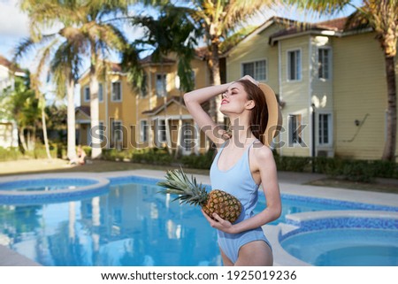 woman in swimsuit in the pool pineapple hands Exotic hotel vacation