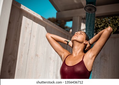 woman in swimsuit showering after swimming in pool and sea, on a hot sunny summer day - Powered by Shutterstock