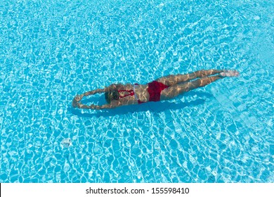 Woman with swimsuit swimming on a blue water pool