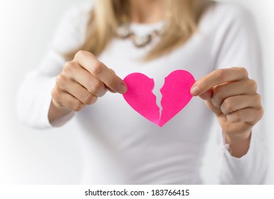 Woman symbolically tearing up pink paper heart