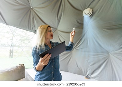 Woman With Tablet Turning On Ventilation System As A Recuperator For Fresh Indoor Air Quality, Smart Home