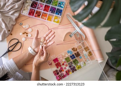 Woman tailor choosing sew button round heart shape creating clothes garment at studio top view closeup. Female fashion designer dressmaker trying material for clothing repair enjoy art hobby work