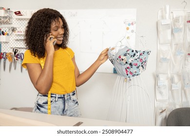 Woman tailor measuring dress on mannequin and talking on smartphone while working in sewing atelier - Powered by Shutterstock