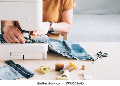 A woman tailor works at sewing machine sews reuses fabric from old denim clothes - Shutterstock ID 1938661645