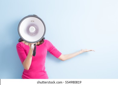 woman take microphone and show something to you isolated on blue background