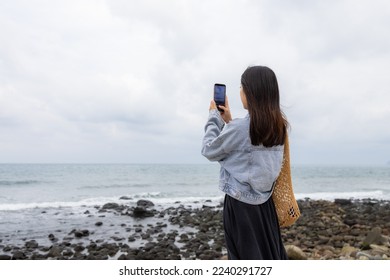 Woman take photo with cellphone of sea beach
