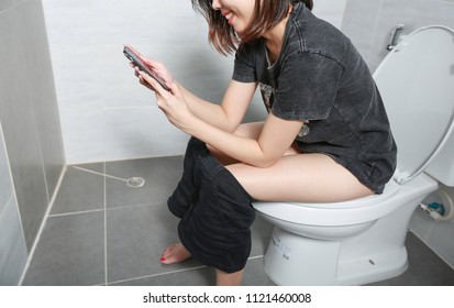 Woman take smart phone and smile happiness in the toilet.