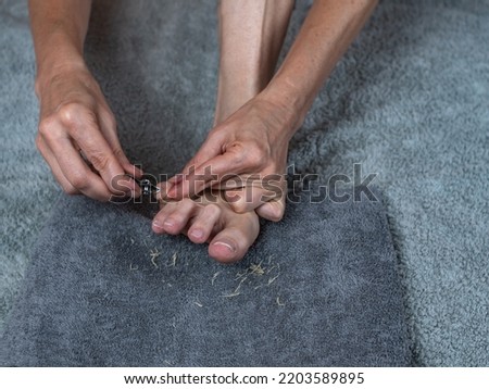 A woman takes care of her feet by cutting the nails of her toes.