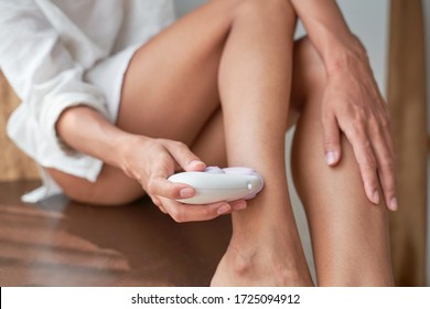 Woman takes care of herself, depilated legs with an epilator, sits on chair, curves of body, sun rays on skin, prepares to go sea summer. Epilation Cosmetology procedure for hair removal. SPA concept. - Shutterstock ID 1725094912
