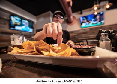 Woman Takes The First Tortilla Chip Off An Appetizer Plate Of Chips And Salsa