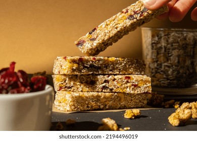 Woman Takes Homemade Granola Energy Bar. Variety Of Protein Granola Breakfast Bars, With Nuts, Raisins Dried Cherries And Chocolate. Healthy Nutrition Eating Gluten Free Cereal Dieting Snack Super