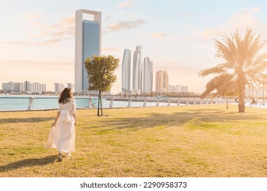 A woman takes a leisurely stroll through the park in Abu Dhabi, enjoying the shade of the palm trees and the cool sea breeze blowing in from the Persian Gulf. - Powered by Shutterstock