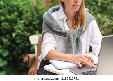 A Woman Takes Notes In Front Of A Laptop During An Online Business Meeting Outside.