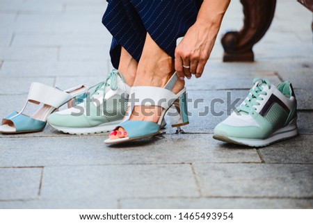 A woman takes off her shoes and wears sneakers for the comfort and health of her legs. Pain in the legs when walking around the city in shoes with heels.