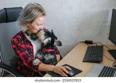 A woman takes a pleasant break from work to cuddle with her small dog at her home office, demonstrating work-life balance - Powered by Shutterstock