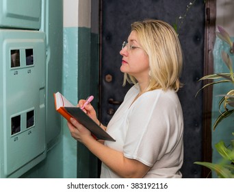 Woman Takes Readings Of The Electric Meter.