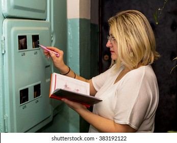 Woman Takes Readings Of The Electric Meter.