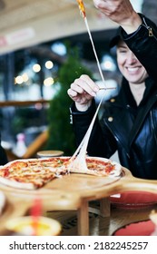 A Woman Takes A Slice Of Pizza At A Pizza Parlor. Pulling Cheese, Yummy Pizza. Vertical Photo.