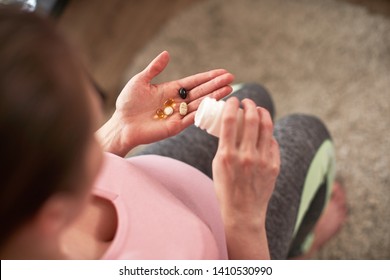 A Woman Takes Vitamins During Pregnancy. Pregnant Girl With A Glass Of Water And A Handful Of Drugs In Her Hand.