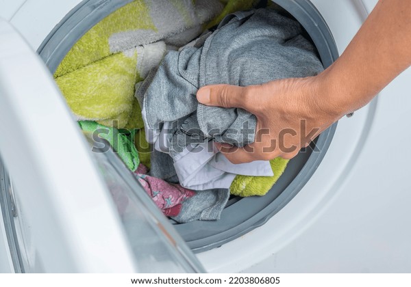 the woman takes the washed clothes out of the
washing machine