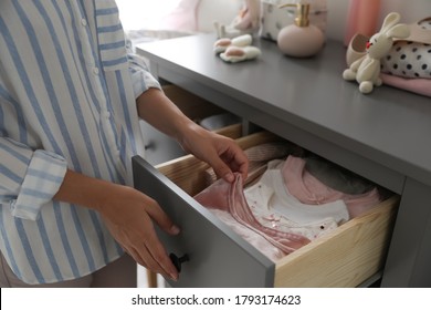 Woman Taking Baby Clothes From Open Cabinet Drawer In Child Room, Closeup