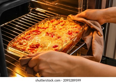 Woman taking baking dish with tasty rice casserole out of oven - Shutterstock ID 2095289599
