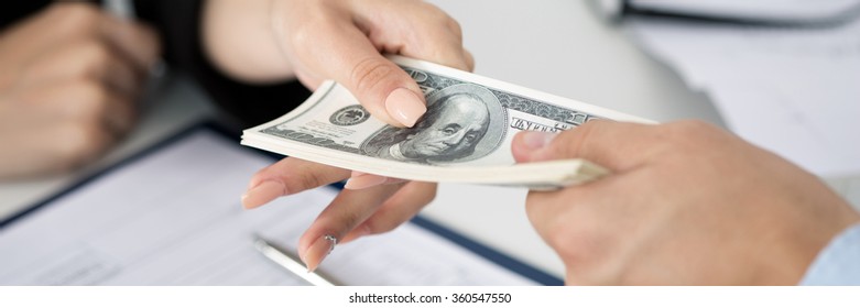 Woman taking batch of hundred dollar bills. Hands close up. Letter box format
