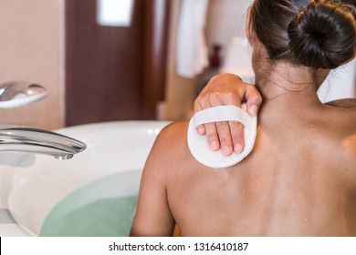 Woman Taking A Bath At Luxury Hotel Scrubbing Back Skin With Hand Scrub Sponge Removing Dead Skin Cells For Body, Skincare Exfoliation. People Skin Care Lifestyle.