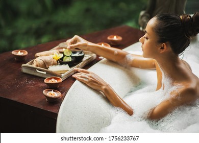 Woman Taking A Bath. Tub With Foam Bubbles. Romantic Spa Treatment, Body Care. Natural Cosmetics Set On Wooden Tray.