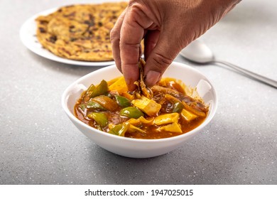 Woman Taking A Bite Of Spicy Paneer Or Chili Paneer Or Paneer Tikka With Capsicum, Onion With Lachha Paratha Served For The Meal