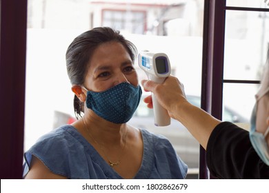 A Woman Taking The Body Temperature Of Another Woman, With A Thermometer