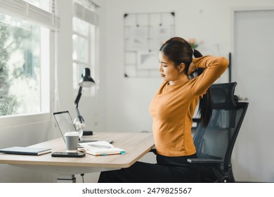 Woman taking a break and stretching at desk in home office - Powered by Shutterstock