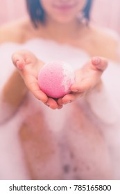 Woman Taking Bubbling Ball for Bath. Toned. Pink.