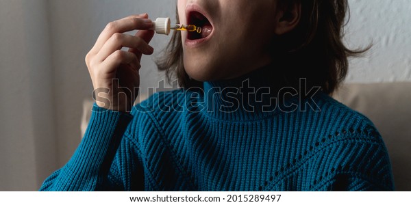 Woman taking cbd oil under tongue -\
Alternative medicine concept - Focus on\
dropper